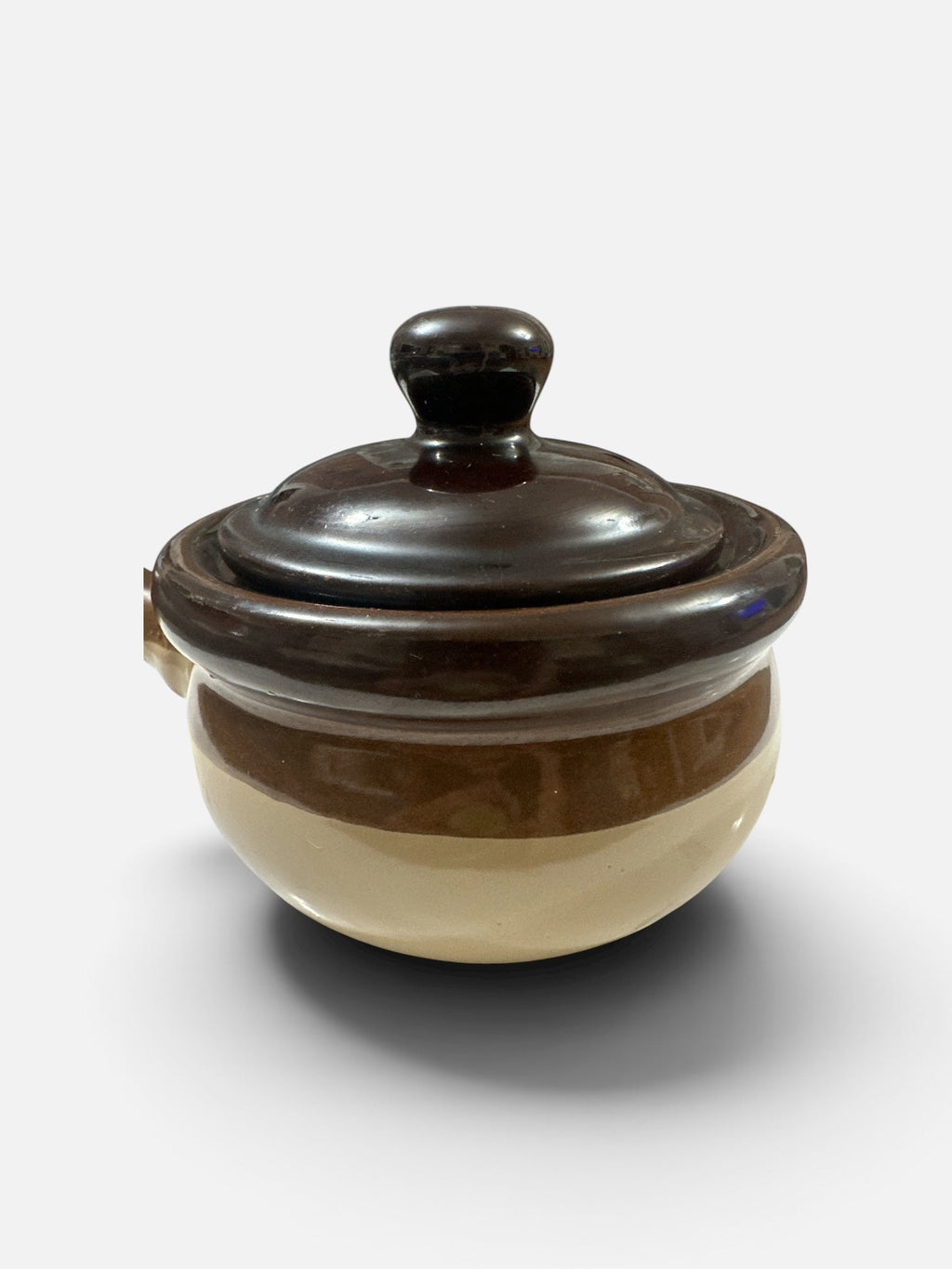 The Collected Chapter vintage brown and cream stoneware crock with a lidded top and side handle in rustic style.