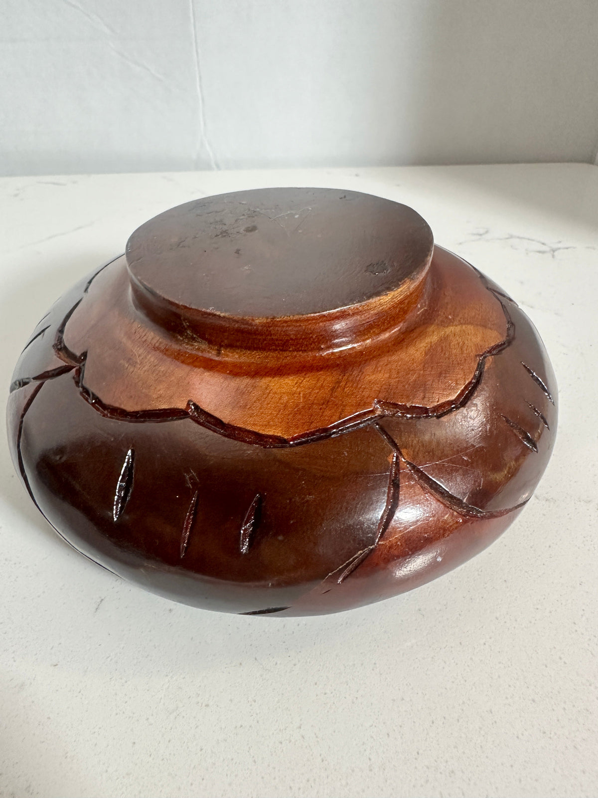 The Collected Chapter vintage hand-carved wood bowl with a reddish-brown finish and leaf pattern on the exterior base.