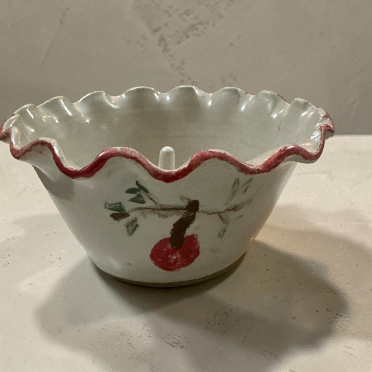 The Collected Chapter handmade ceramic apple baker with creamy white glaze, ruffled edge, and painted apple branch.