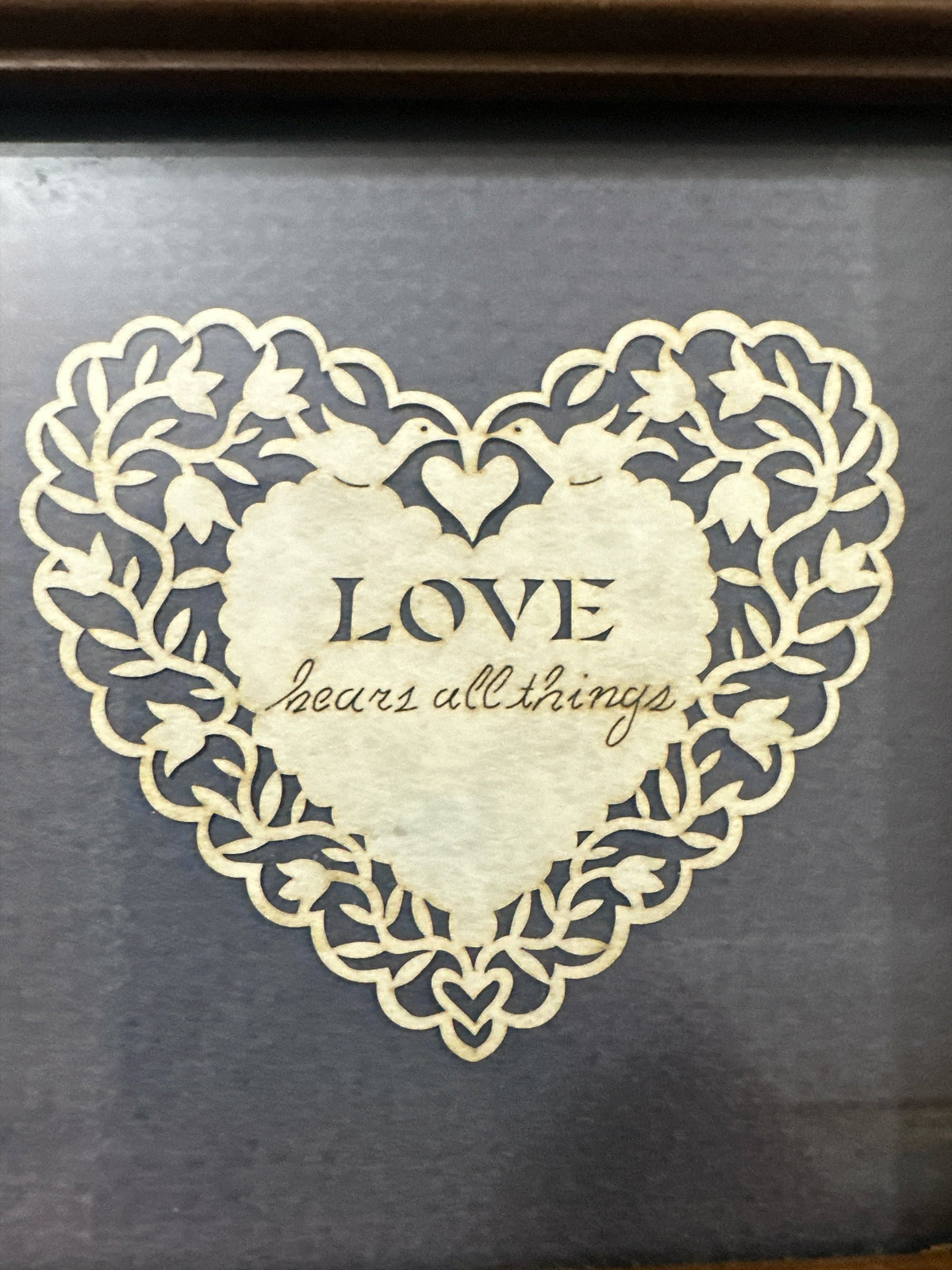 The Collected Chapter vintage Cindy Jacobs Ltd paper cut heart art with Love Bears All Things text on charcoal background