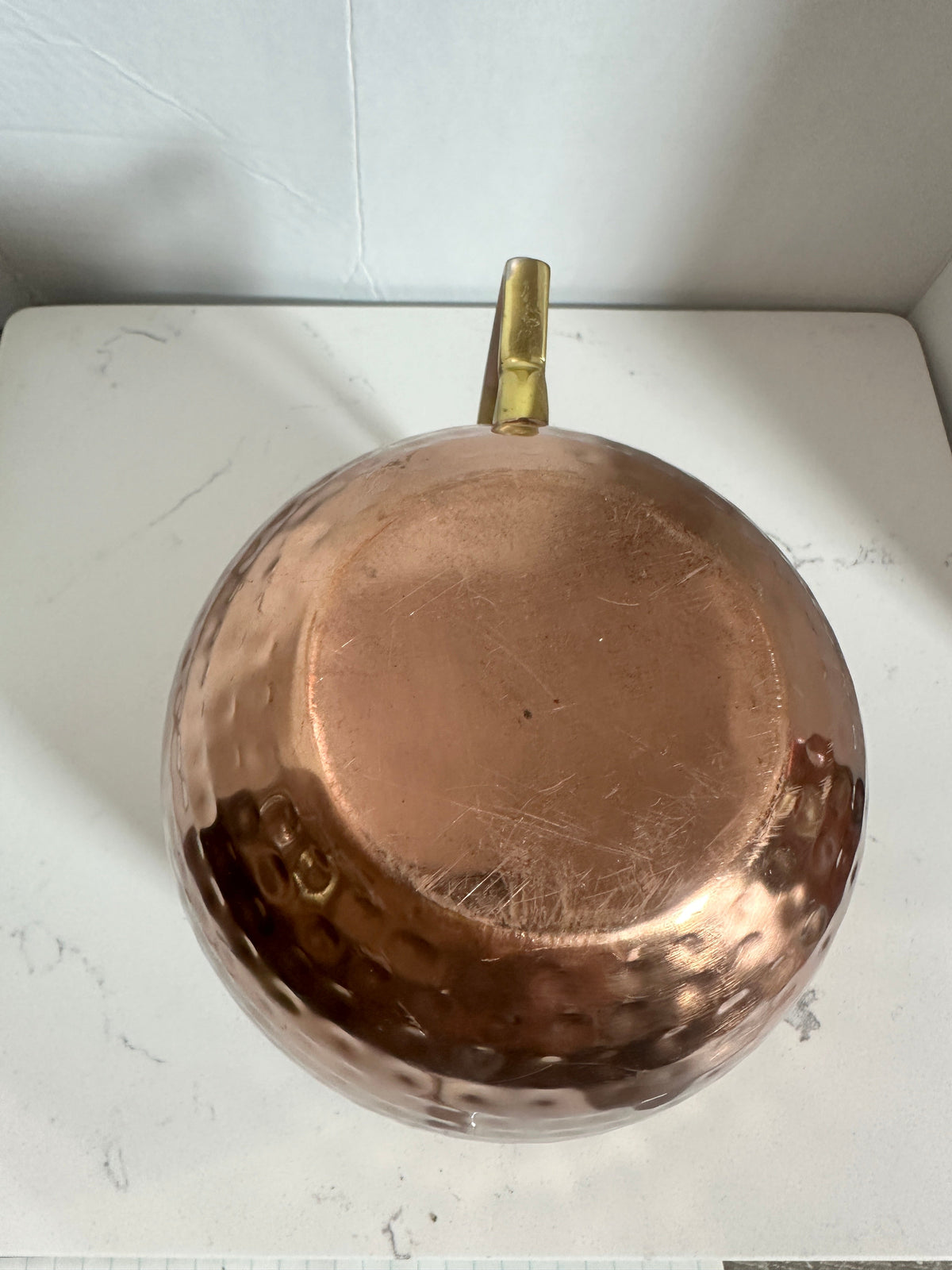 The Collected Chapter oversized hammered copper-tone tankard with brass handle viewed from above on a white surface.
