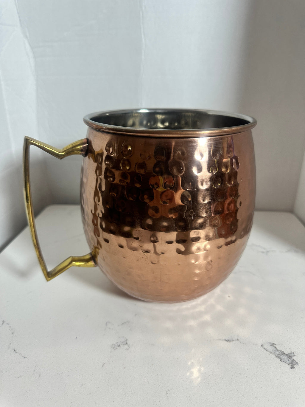 The Collected Chapter oversized hammered copper-tone tankard with a brass-tone angular handle and steel interior.