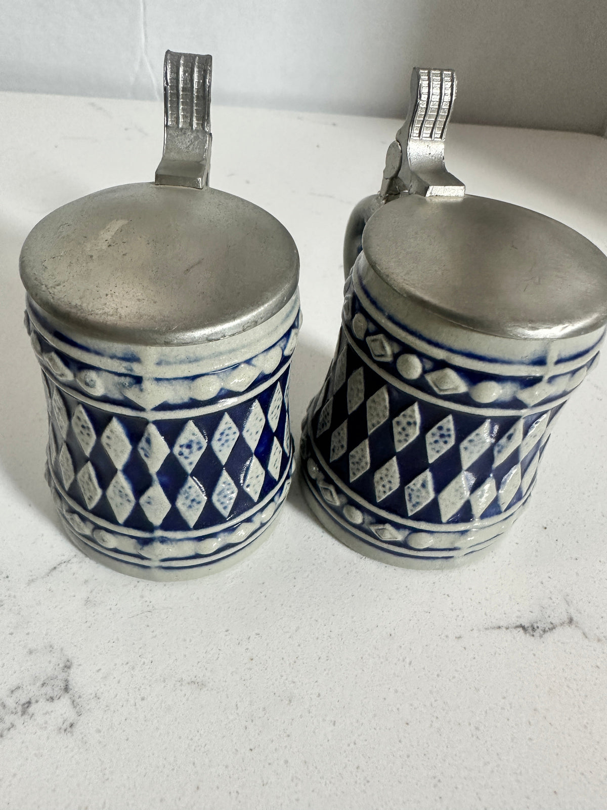The Collected Chapter pair of vintage miniature ceramic beer steins with cobalt blue diamond patterns and metal lids.