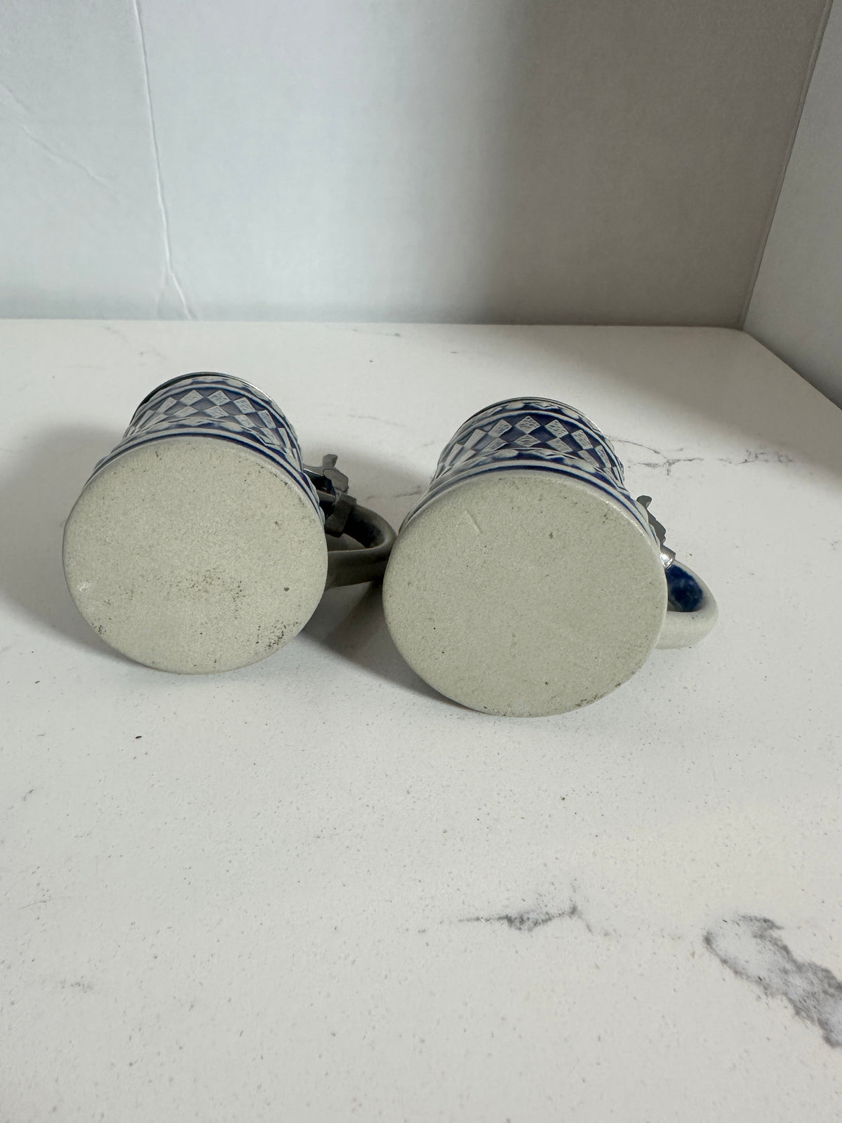 The Collected Chapter vintage miniature beer steins showing the plain ceramic bases of the blue and white mugs.