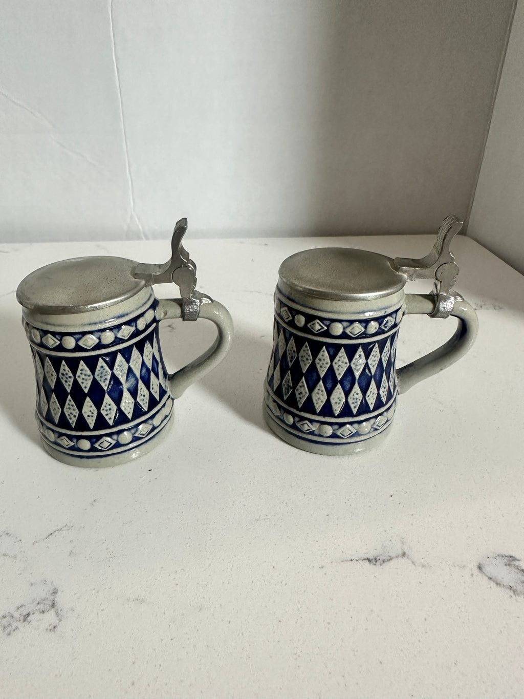 The Collected Chapter pair of vintage miniature beer steins with cobalt blue and cream Bavarian diamond patterns.