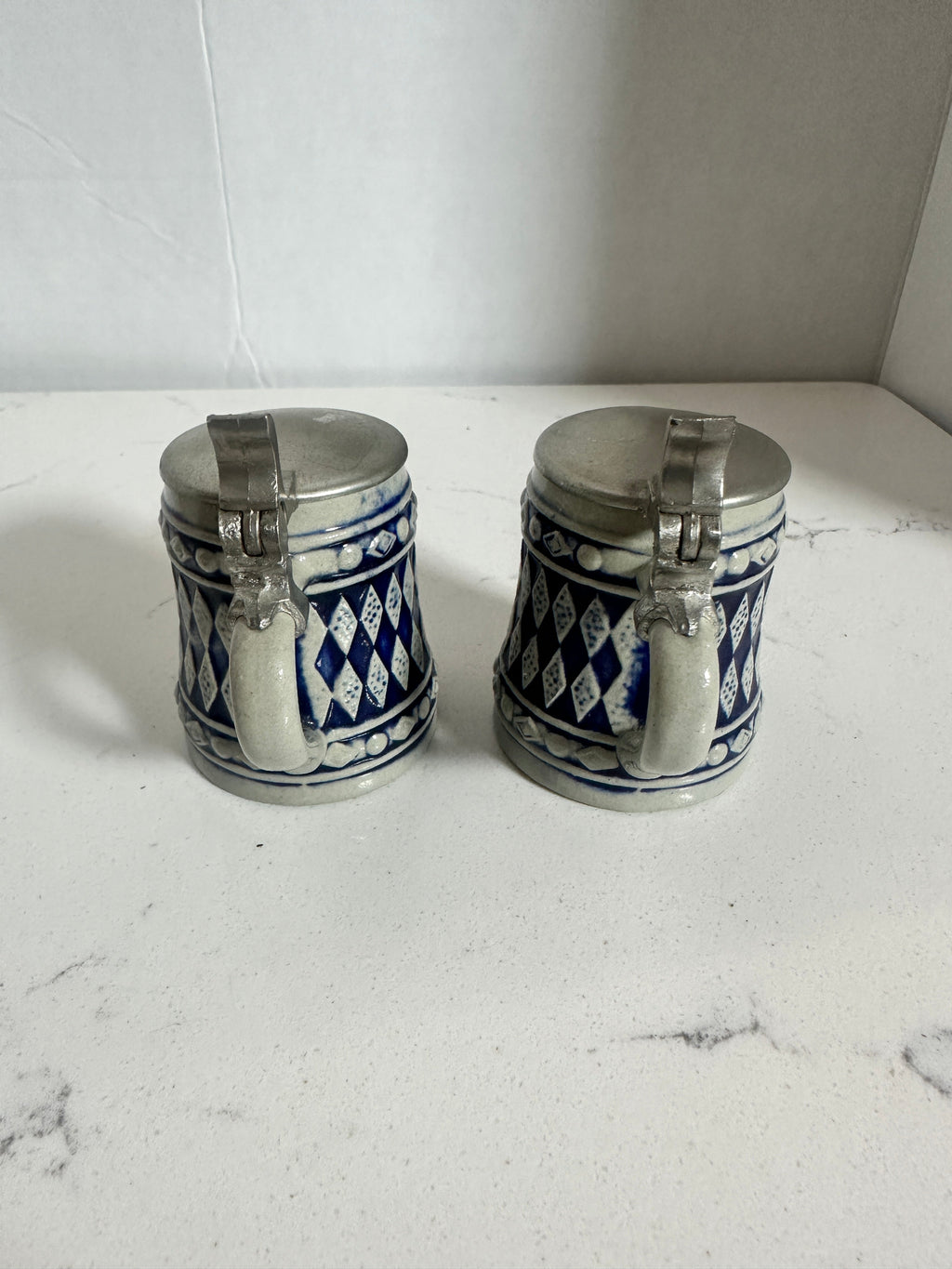 The Collected Chapter pair of vintage miniature ceramic beer steins with cobalt blue diamond patterns and metal lids.