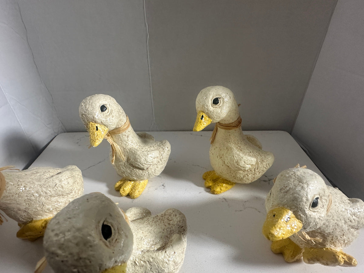 The Collected Chapter set of 5 rustic cream and yellow duck figurines with raffia neck accents and textured finish.