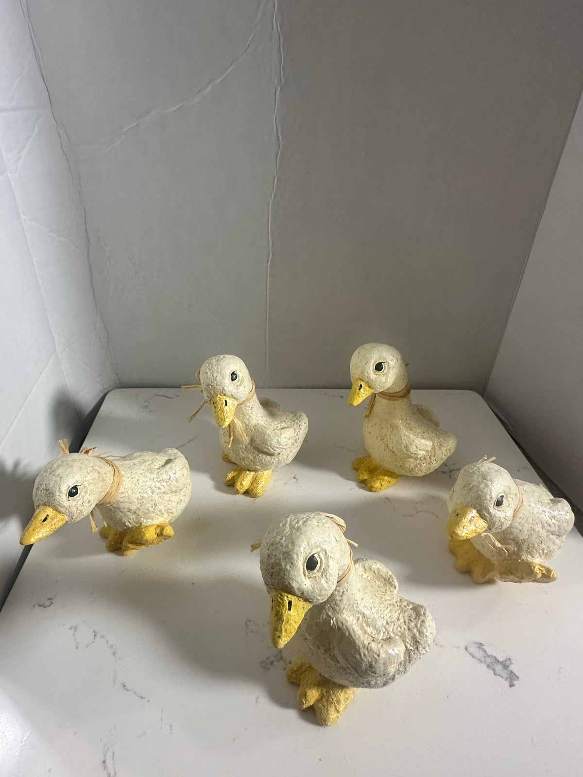 The Collected Chapter set of five rustic cream and yellow duck figurines with raffia neck accents and glitter finish.