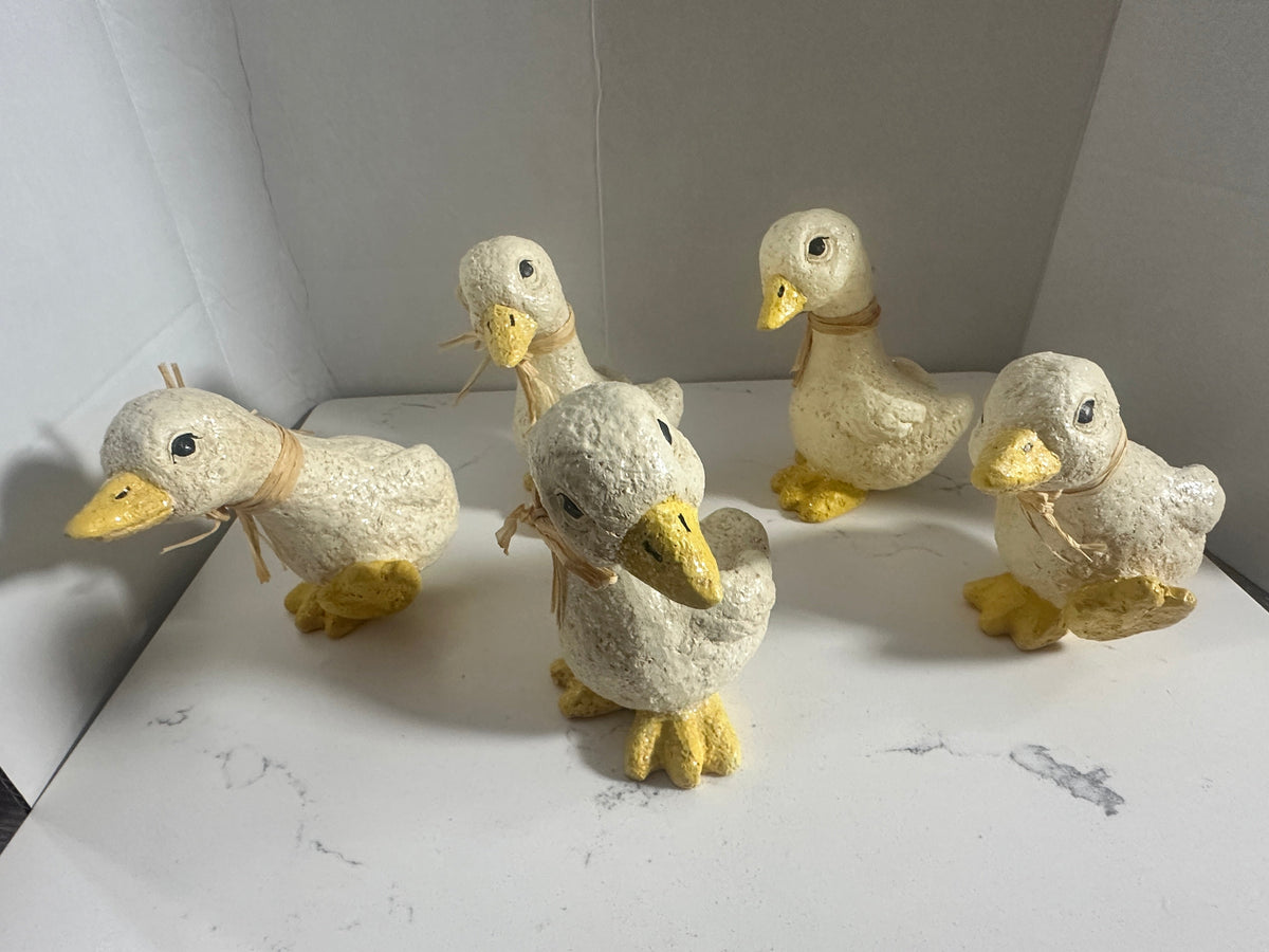 The Collected Chapter set of five rustic cream and yellow duck figurines with raffia neck ties and glitter accents.