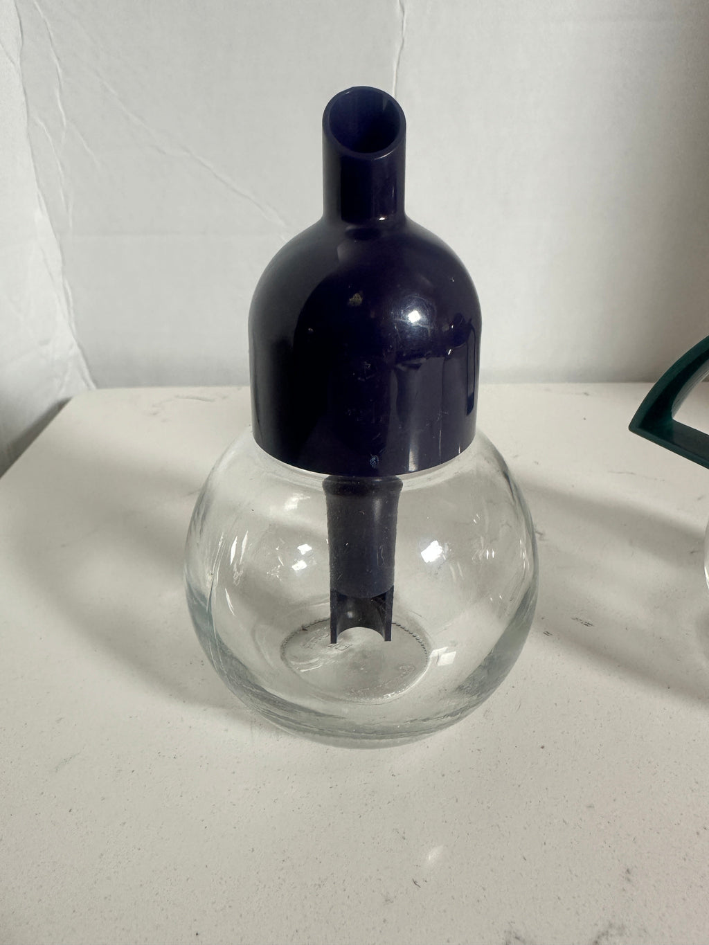 The Collected Chapter vintage STOHA Germany glass condiment dispenser with a deep blue plastic top on a white surface.