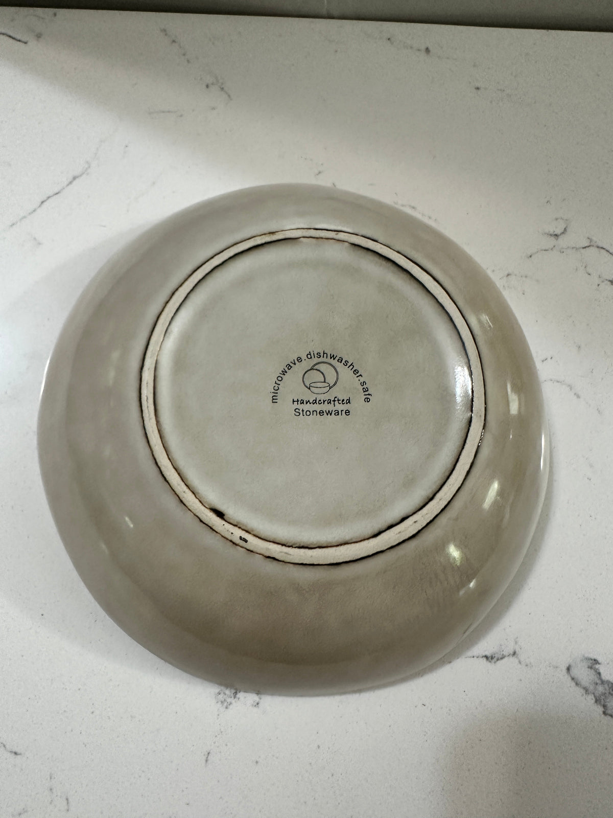 The Collected Chapter AmorArc stoneware bowl base showing microwave and dishwasher safe stamp on beige reactive glaze