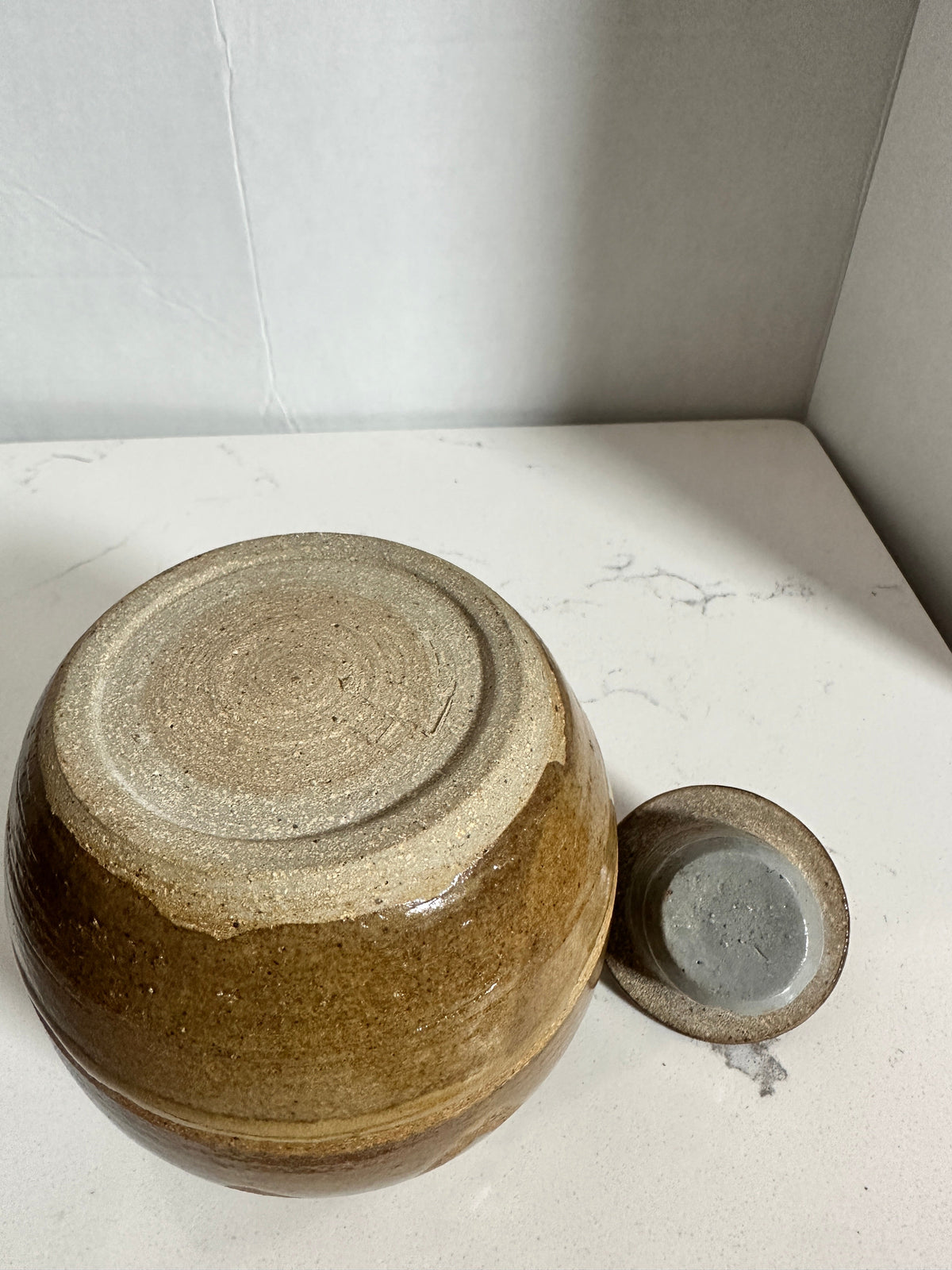 The Collected Chapter vintage stoneware lidded jar with brown glaze and hand-thrown base, viewed from above.