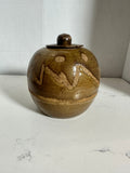 The Collected Chapter vintage handmade stoneware lidded jar with brown and tan abstract glaze and round pottery form.