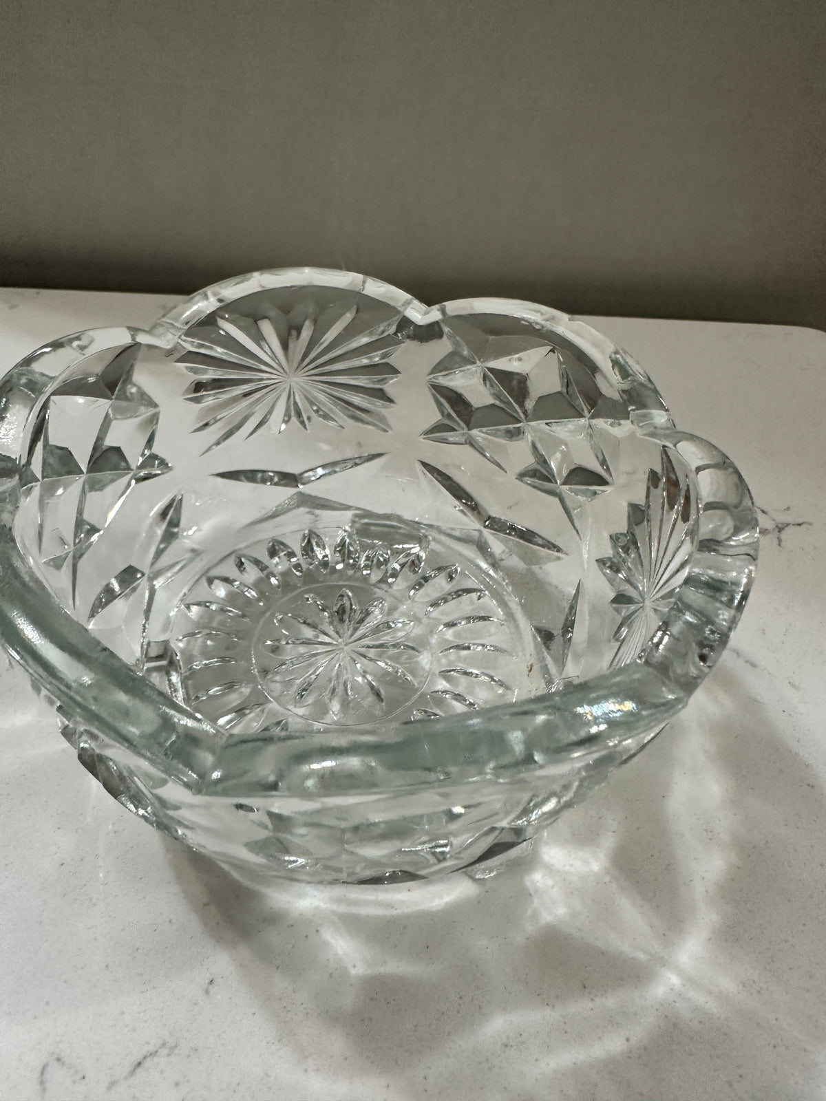 The Collected Chapter vintage clear crystal bowl with starburst and pinwheel patterns and a scalloped rim.