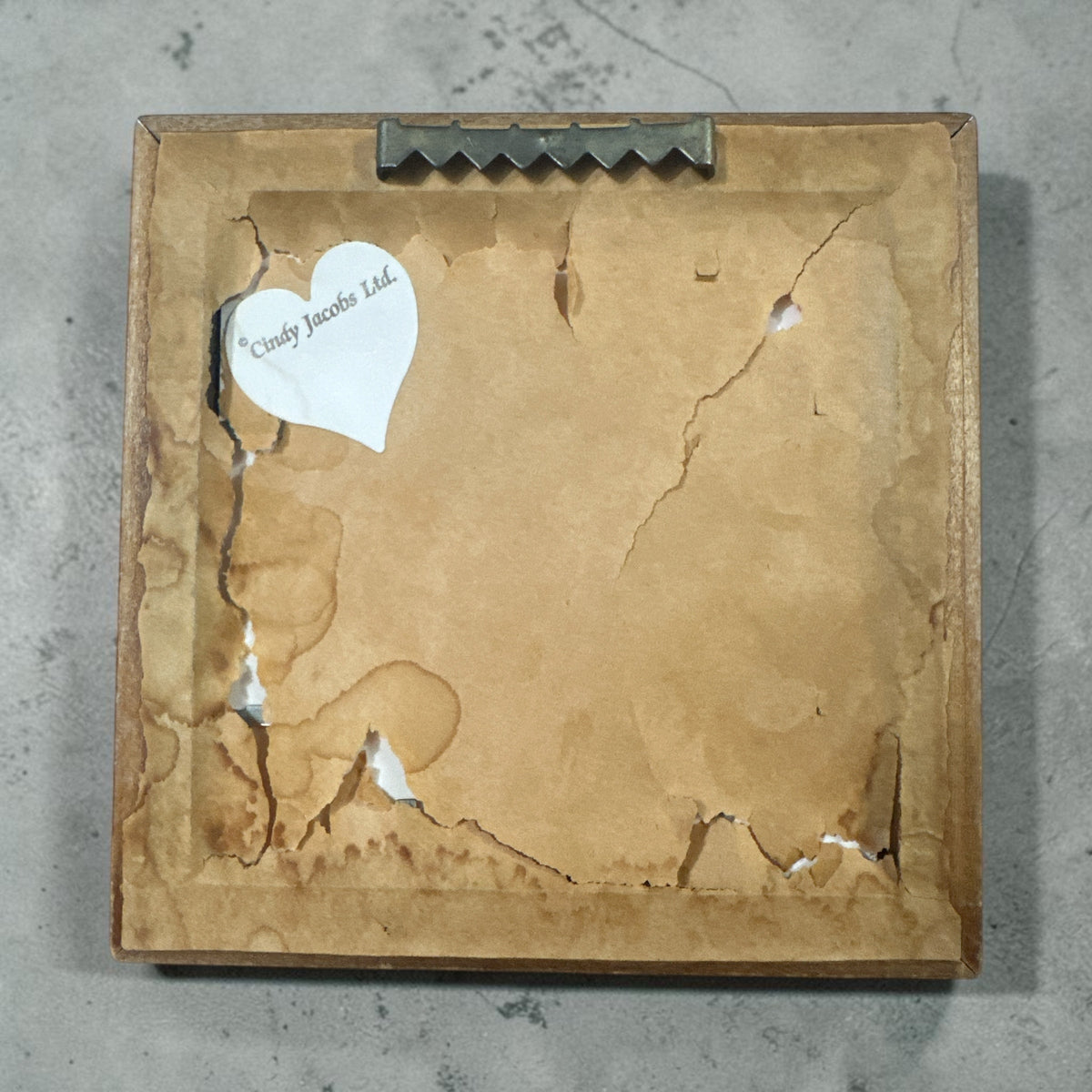 The Collected Chapter vintage Cindy Jacobs Ltd framed paper art showing the aged and torn paper backing with a logo