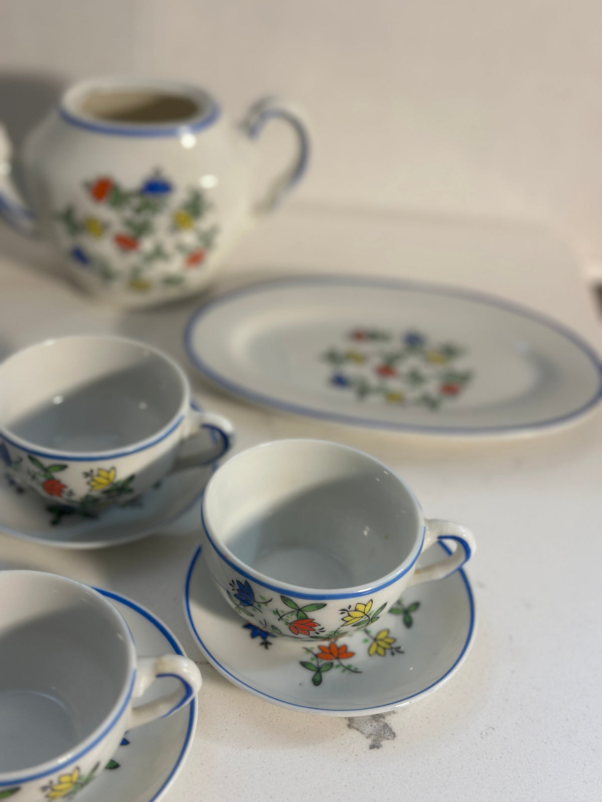 The Collected Chapter vintage miniature porcelain tea set with floral pattern and blue trim on a white surface.