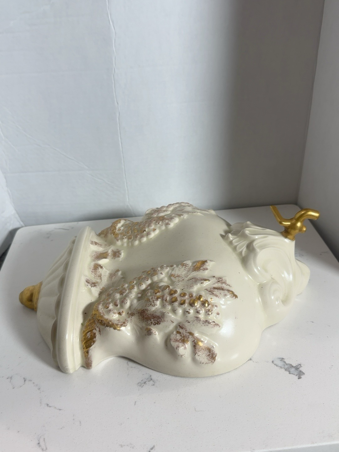 The Collected Chapter vintage cream resin wall dispenser with gold grape and vine relief and decorative spigot.