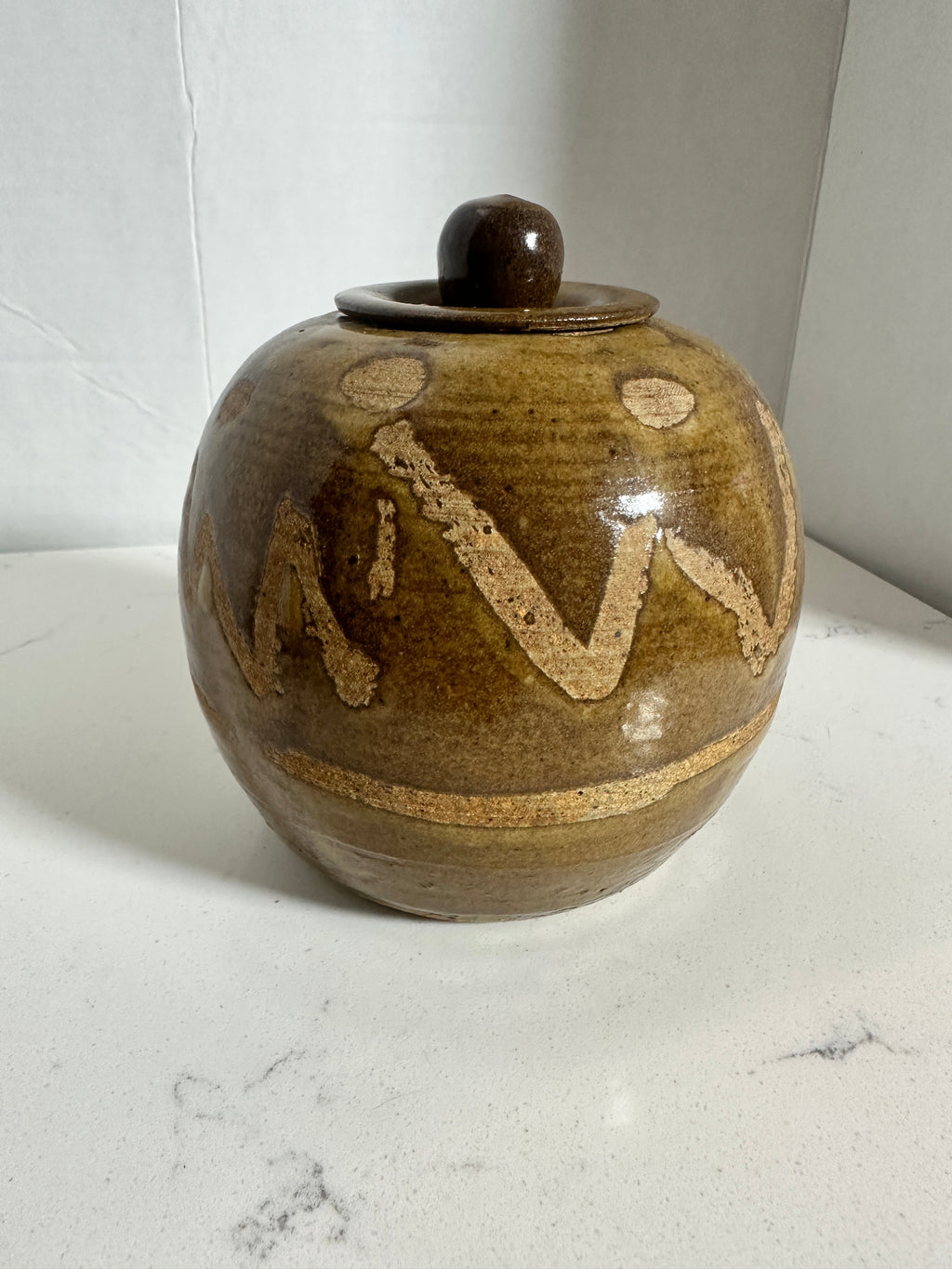 The Collected Chapter vintage handmade stoneware lidded jar with brown and tan glaze and abstract geometric pattern.